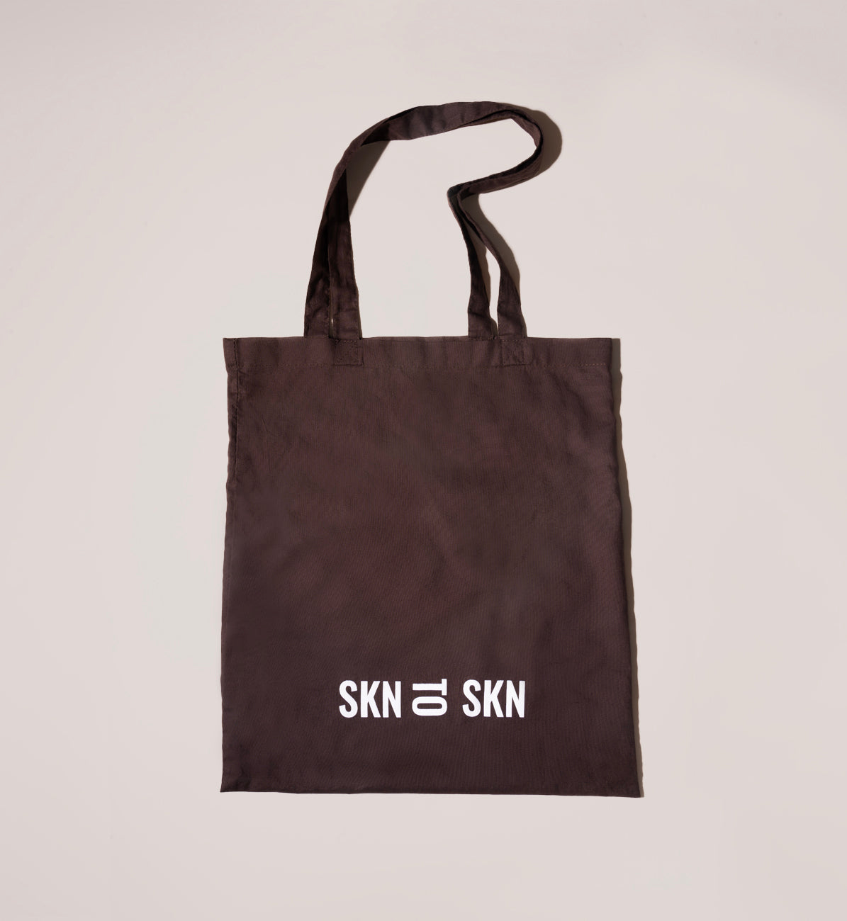 brown tote bag with skn to skn logo